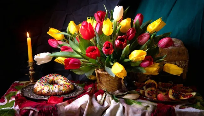 Farbiges Stillleben mit Tulpen, Gebäck und einer brennenden Kerze